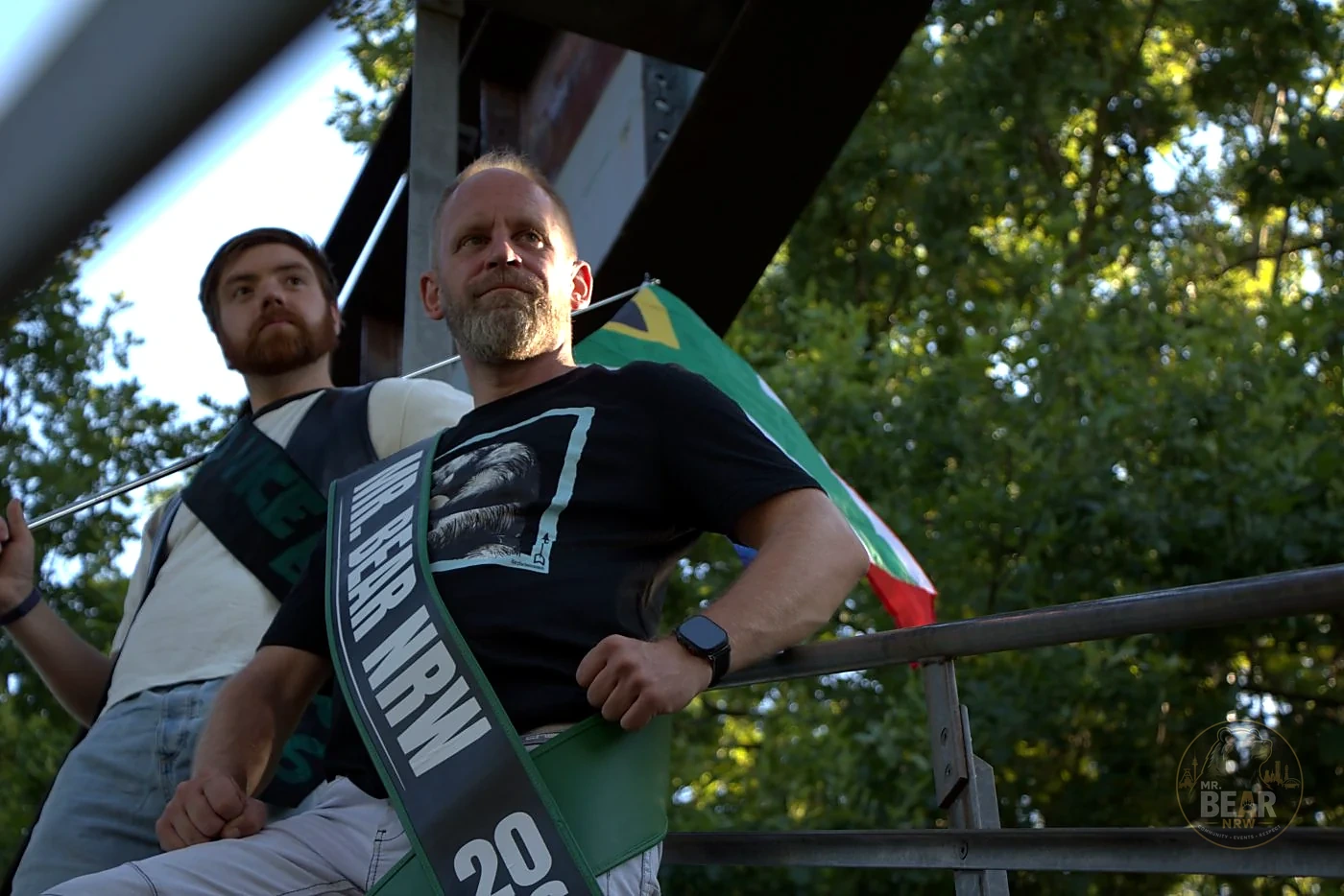 Christoph und Joshua vor der NRW-Flagge an einer Stahltreppe