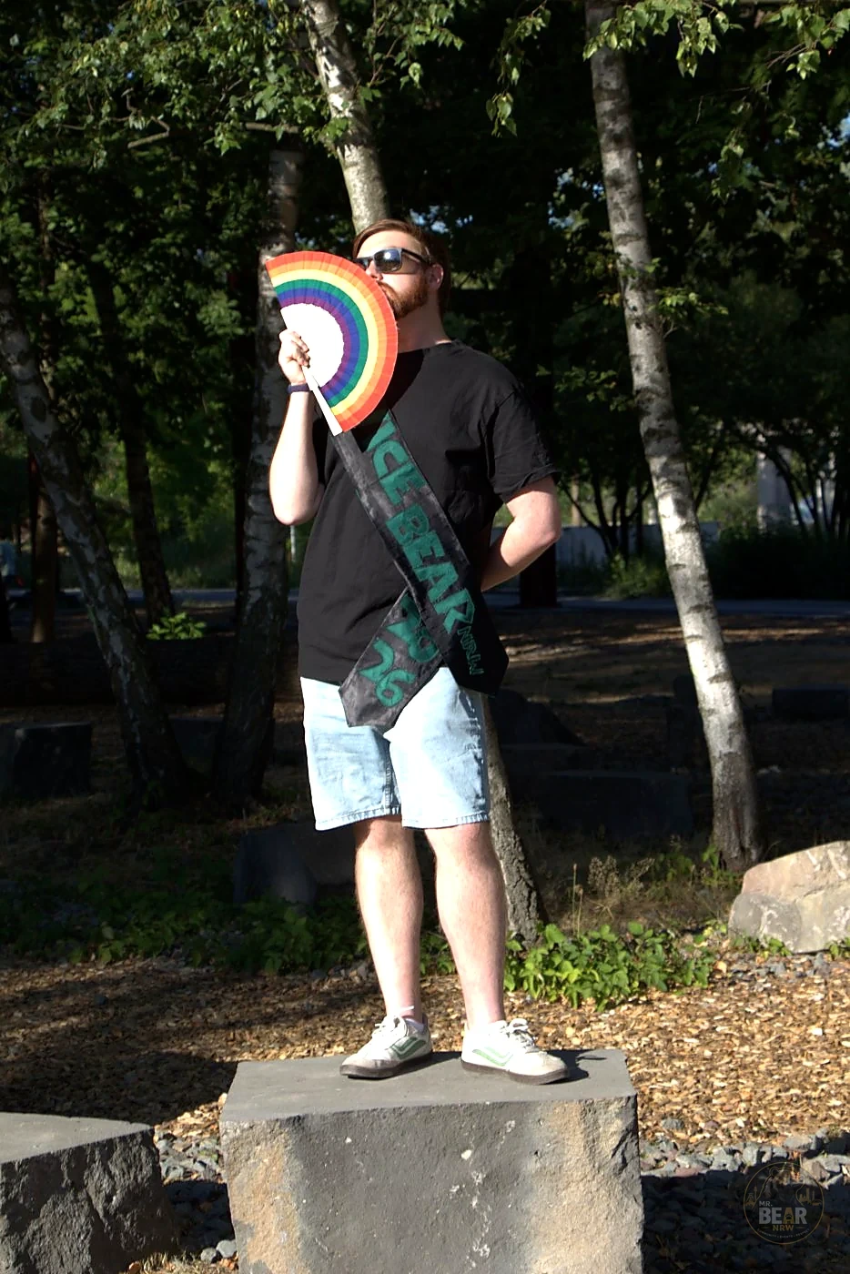 Joshua mit der Schärpe Mr. Vice Bear NRW und Pride-Fächer